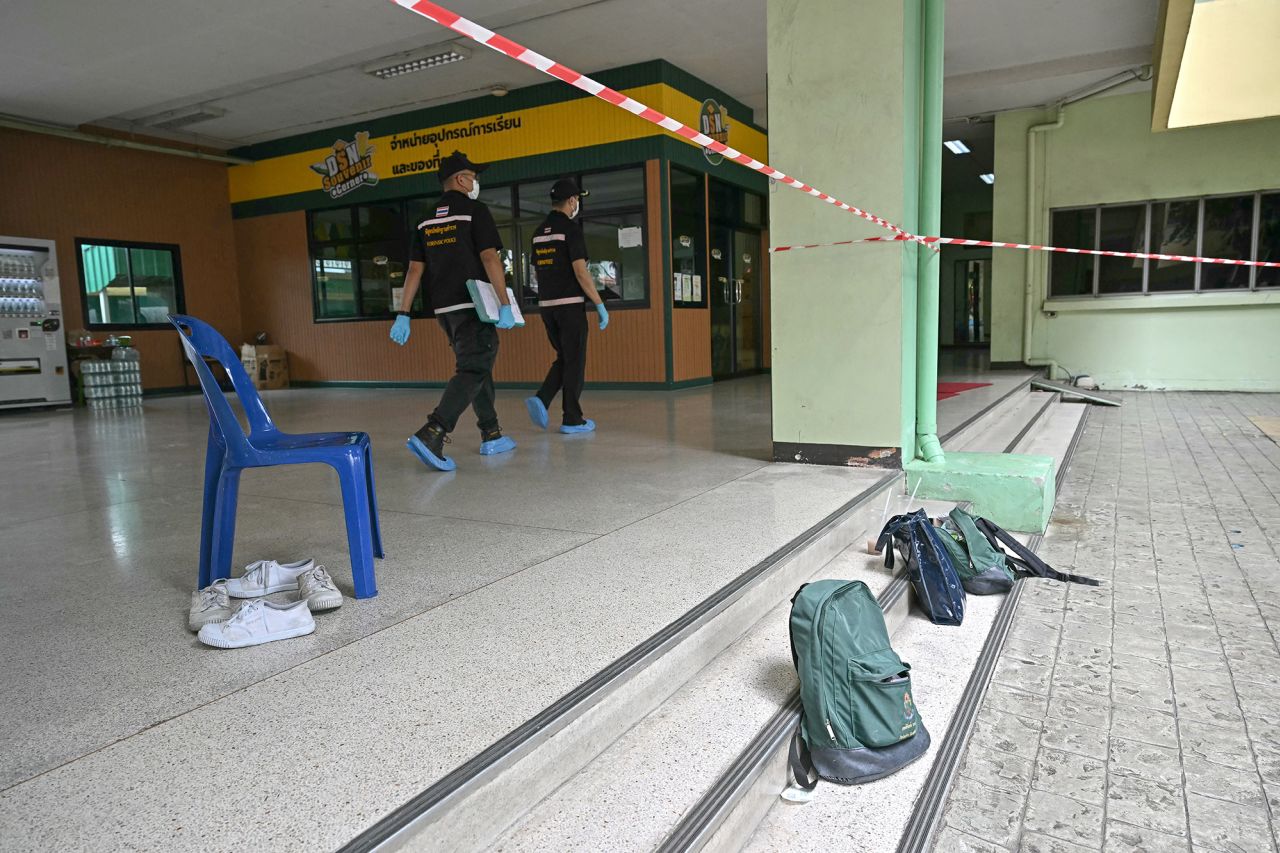Students' belongings are left at the scene of a school shooting as forensic police walk past.