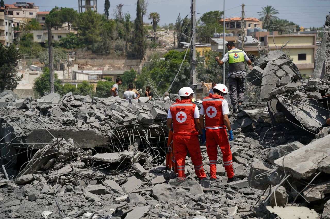 First aid responders and residents rush to the site of an Israeli airstrike that targeted a neighborhood in the southern Lebanese village of Deir al-Zahrani on Saturday.
