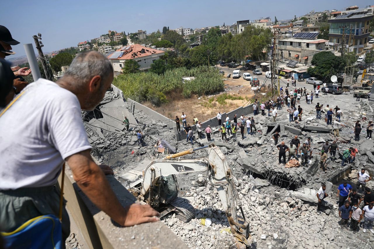 A man watches first aid responders and residents search the site of an Israeli airstrike in Deir al-Zahrani, Lebanon on Saturday.