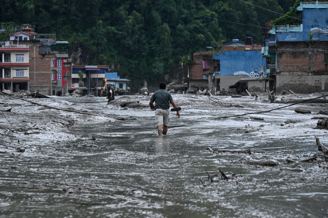 A man walks through a mud-covered street in Nepal's Nuwakot district on August 26.