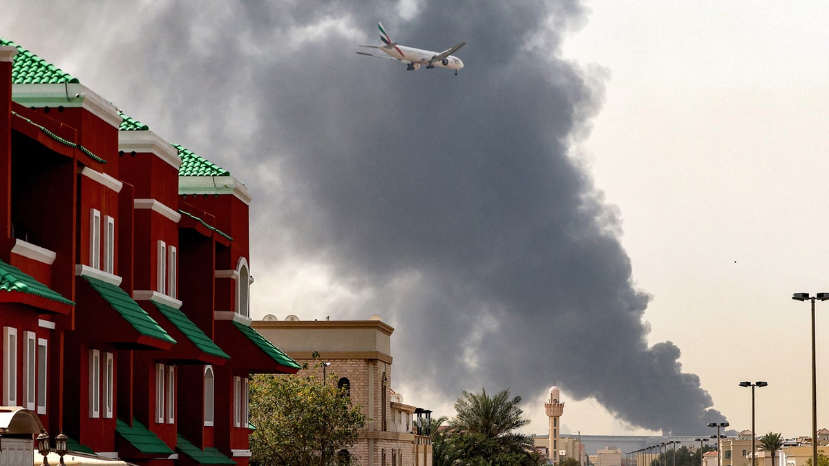 plane flying over smoke and buildings in dubai