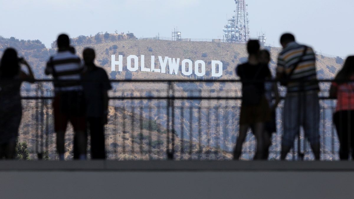Tourists take pictures of the Hollywood sign from a shopping complex along Hollywood Boulevard in Hollywood, California, U.S. August 3, 2017. REUTERS/Mike Blake - RC1B0A1F9E40