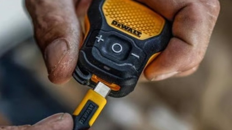 A person plugging a USB-C cable into the DeWalt mini speaker