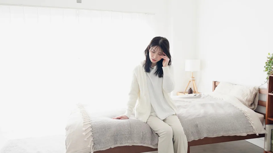 Tired person sitting on the edge of the bed, illustrating why motivation-based routines fail