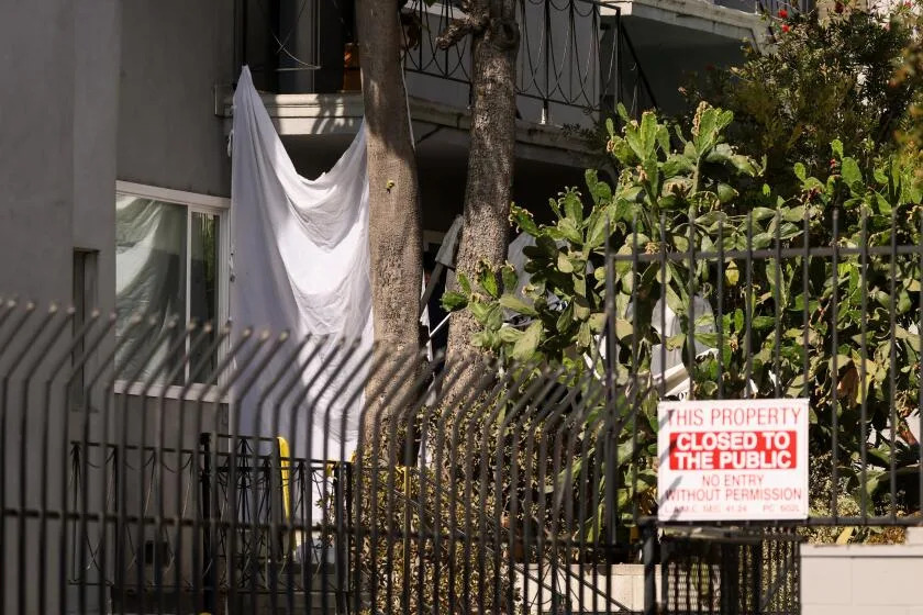 A plastic sheet blocks the window of an apartment where three people were shot dead in Hollywood in July.
