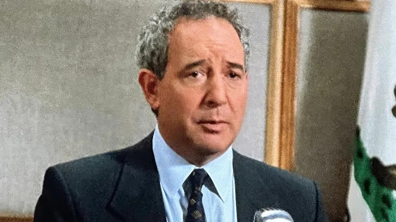 Stuart Markowitz in a black suit standing in front of a microphone in L.A. Law