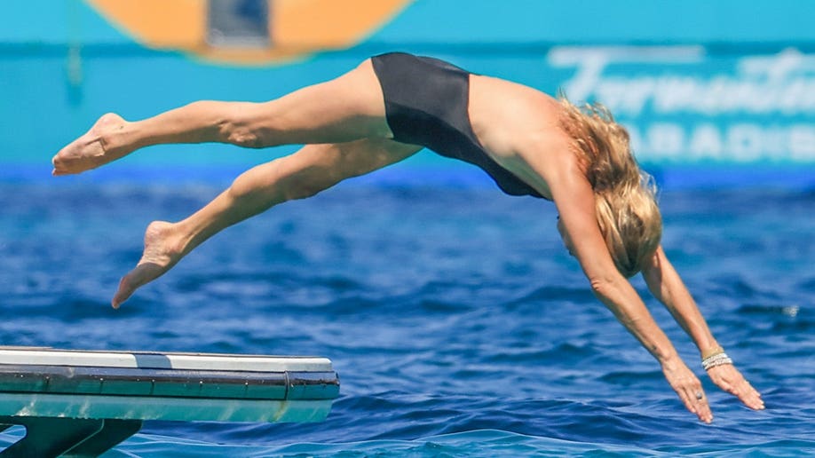 Kate Moss diving into the water while in a black one-piece in Spain.