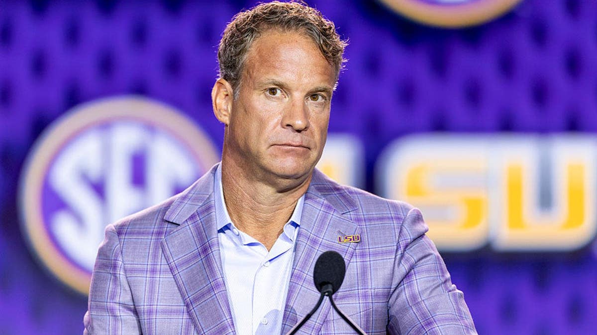 Lane Kiffin speaks at a podium during SEC Football Kickoff Media Day.