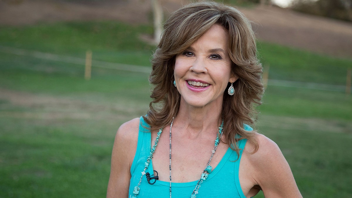Linda Blair smiling in a turquoise tank top