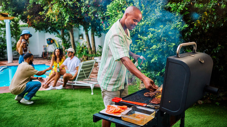 Family in a backyard with one man grilling food