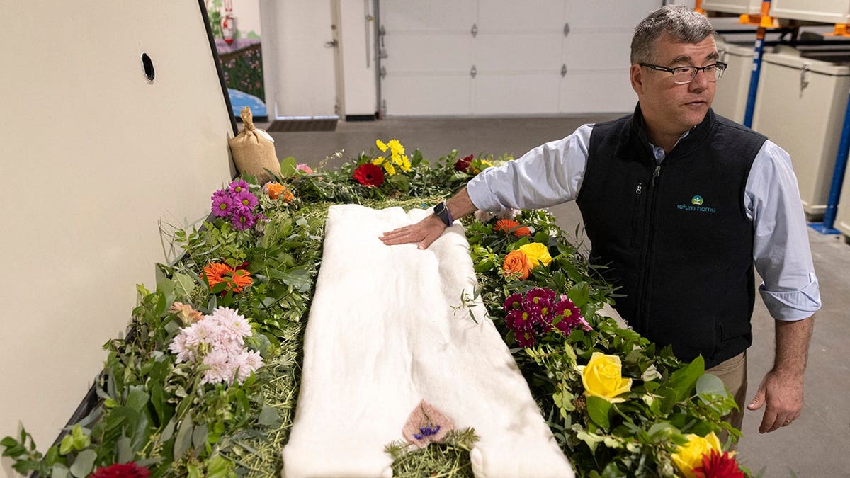 Micah Truman, CEO of Return Home, displays a demonstration vessel decorated with flowers and compostable mementos.