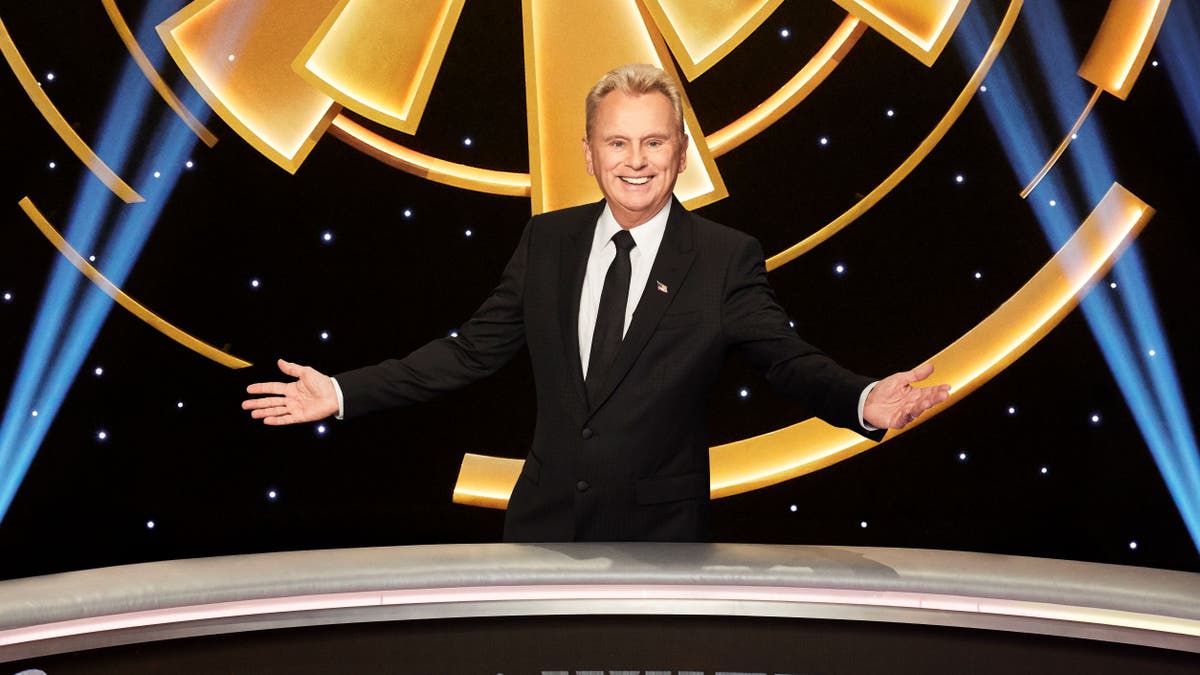 Pat Sajak proudly stands with arms wide open on