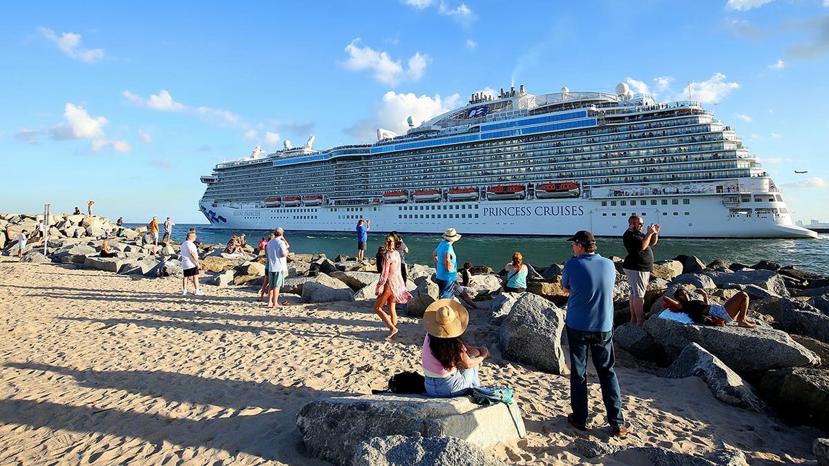 Tourists and sightseers photograph departing cruise ships at Port Everglades jetty.