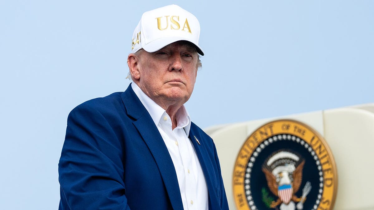 President Donald Trump wearing a white hat with gold