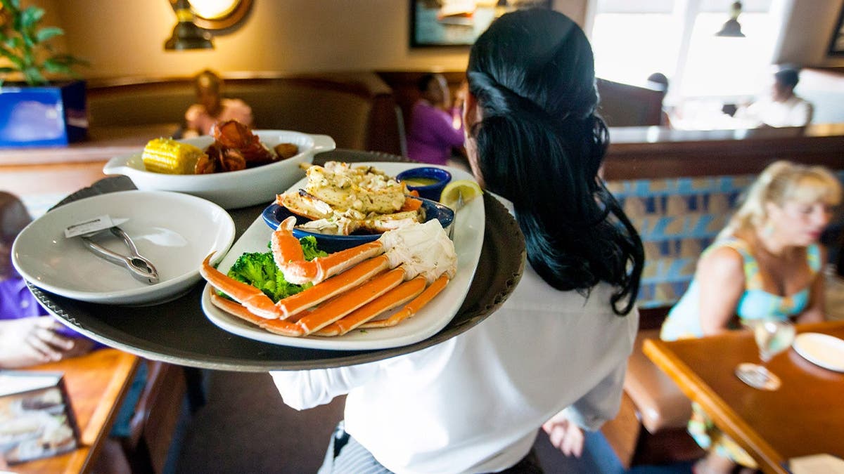 A Red Lobster waitress carries a tray of food.