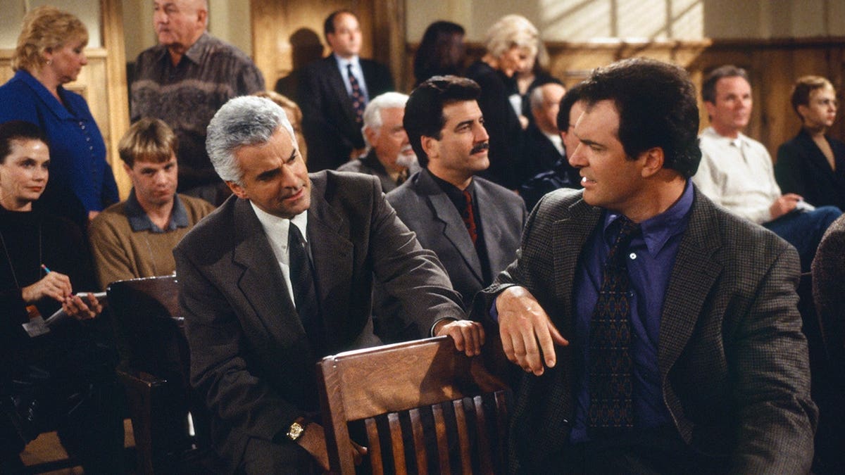Patrick Warburton, John O'Hurley, and Keith Hernandez stand together in a scene from Seinfeld.