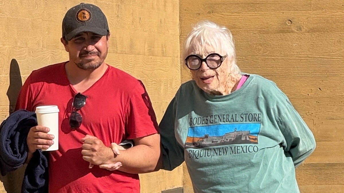 Shirley MacLaine in a green shirt walking with a man in a red shirt while out in Los Angeles in January 2026.