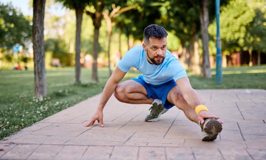 Perons outside on paved path stretching their leg