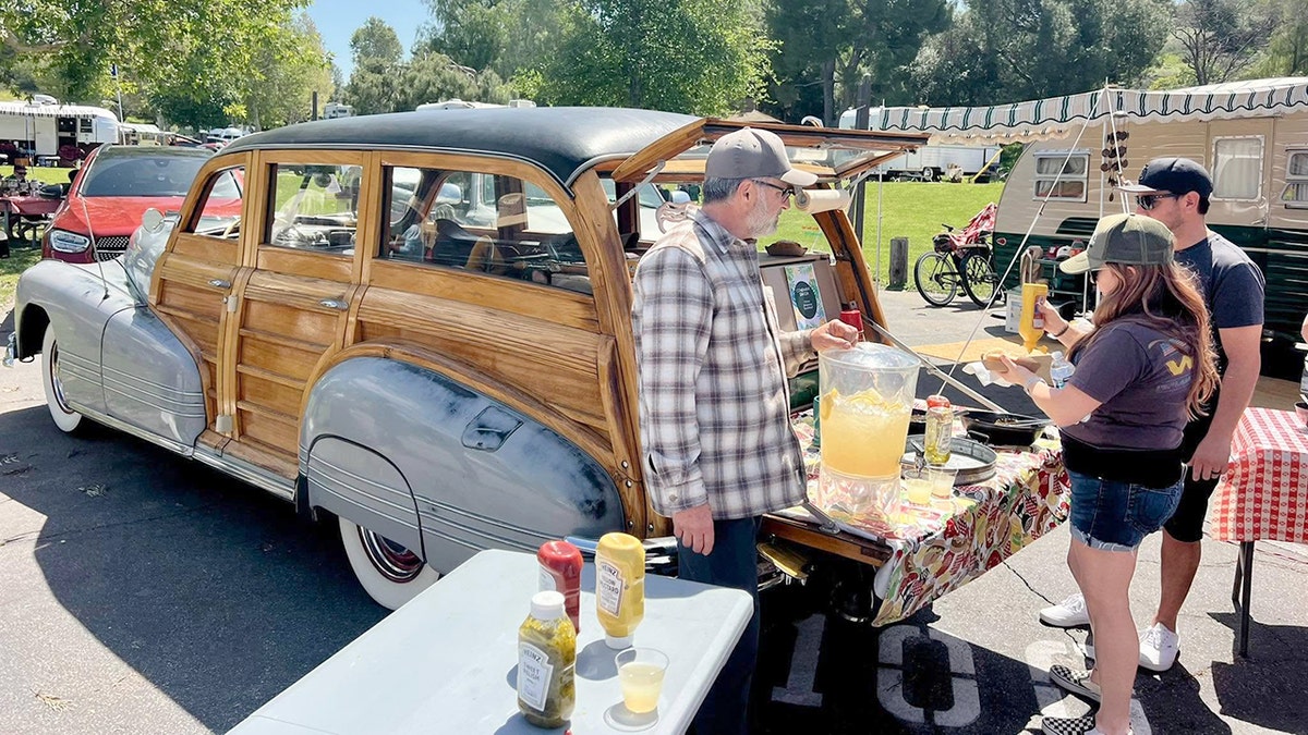 A woman puts mustard on her hot dog during a vintage camper trailer rally.