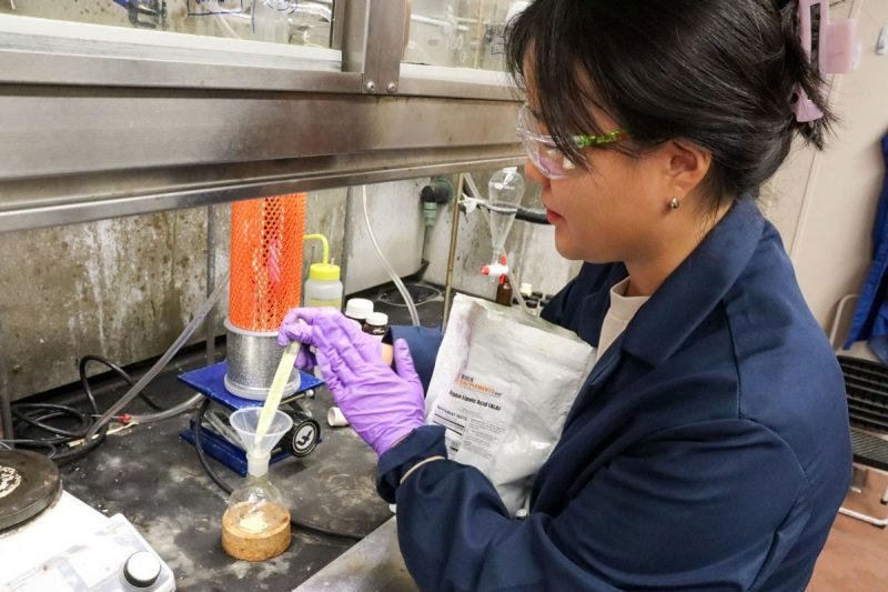 Woman putting something into a vial in a lab setting